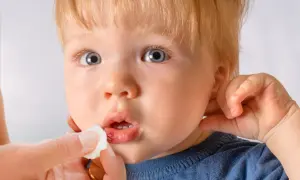 Ein Kind mit blauen Augen und blonden Haaren bekommt die Lippe mit einem Tupfer versorgt. Die Lippe zeigt eine kleine, blutende Platzwunde.