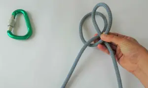 Hand knotet Seil, ein Karabiner liegt daneben. Dies ist der beste Knoten für Sicherheit.