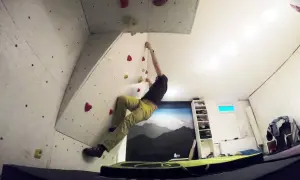 Mann klettert an einer selbstgebauten Boulderwand. Bunte Griffe sind auf der Wand verteilt.