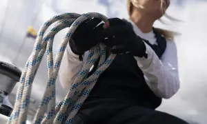 Seglerin mit Handschuhen hält ein dickes Seil. Die Knotentechnik Seil ist entscheidend für die Sicherheit auf See.