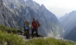 Zwei Wanderer mit Rucksäcken genießen die Aussicht auf die Berge bei Garmisch.