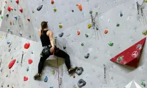 Frau beim Bouldern, sucht nach den nächsten Griffen. Gute bouldern tipps helfen, die Route zu meistern.