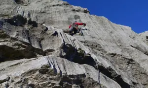 Marcel Dettling klettert eine steile Felswand empor, gesichert durch ein Seil. Der blaue Himmel bildet einen starken Kontrast zum grauen Gestein.