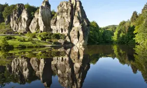 Felsformationen im Teutoburger Wald spiegeln sich in einem ruhigen See.
