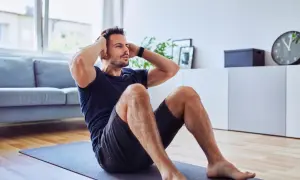 Mann macht Sit-ups auf einer Matte. Er trainiert trotz eines möglichen Rippenbruchs, um fit zu bleiben.