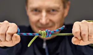 Mann zeigt einen Knoten an zwei Seilen. Eine detaillierte Knoten Anleitung für Bergsteiger.