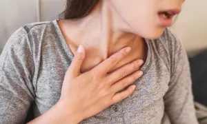Frau mit Hand auf der Brust, die nach Luft ringt, Anzeichen eines allergischen Schocks.