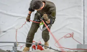 Mann in Uniform übt das Abseilen nur mit Seil. Er hält das Seil fest und kontrolliert den Abstieg.