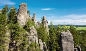 Felsformationen im Adersbacher Felsenlabyrinth, ideal zum Klettern in Tschechien. Grüne Bäume und blauer Himmel.