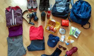 Packliste Wandern Mehrtagestour: Kleidung, Rucksäcke, Kamera, Verpflegung, Trinkflasche, Schuhe, Hut, Sonnenbrille, Regenschirm und Karten für die Tour.
