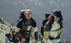 Drei Wanderer mit Rucksäcken steigen einen Bergpfad hinauf. Wie viele Kilometer schafft man wohl in 2 Stunden?