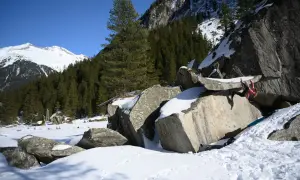Eine Person klettert an einem Felsen im verschneiten Zillertal. Bouldern im Schnee ist eine Herausforderung!