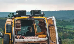 Gelbes Campervan mit gemütlichem Innenraum, bereit für wildcampen in Europa. Dachgepäckträger, Ersatzrad und Stauraum für Abenteuer.