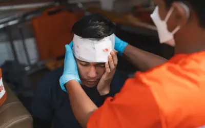 Sanitäter versorgt eine Platzwunde am Kopf eines jungen Mannes mit Verband.