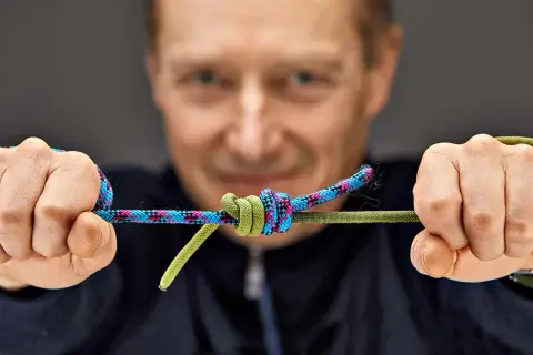 Mann zeigt einen Knoten an zwei Seilen. Eine detaillierte Knoten Anleitung für Bergsteiger.