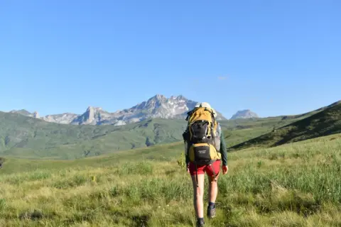 Wanderer auf einem **high scardus trail** mit Rucksack vor majestätischer Bergkulisse.
