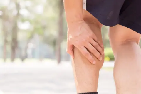 Mann hält sich die Wade, die sich wie ein Pferdekuss anfühlt.