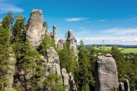 Felsformationen im Adersbacher Felsenlabyrinth, ideal zum Klettern in Tschechien. Grüne Bäume und blauer Himmel.