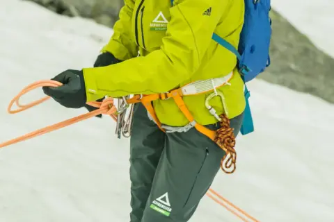 Bergsteigerin bindet mit geübten Händen einen halbmastwurf knoten. Die Seile sind bereit für die nächste Tour.