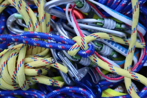 Bunte Kletterseile und Karabiner sind zu einem Gewirr aus Knoten, Knoten und mehr Knoten verheddert.