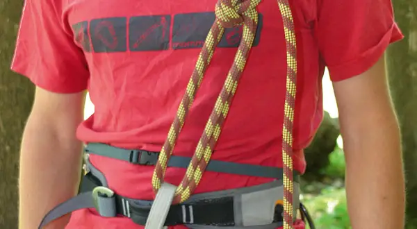 Klettergurt aus Seil binden: Ein Bergsteiger knotet das Seil sicher am Gurt.