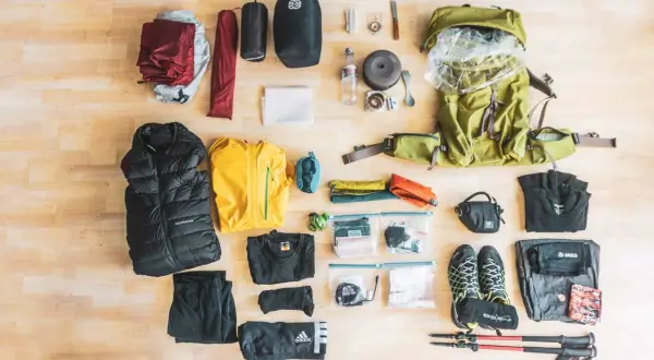 Die Übersicht zeigt eine vollständige **Trekking-Packliste**: Rucksack, Zelt, Schlafsack, Kleidung, Schuhe, Wanderstöcke und Kochutensilien.