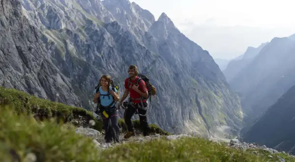 Zwei Wanderer mit Rucksäcken genießen die Aussicht auf die Berge bei Garmisch.