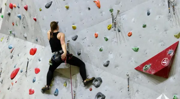 Frau beim Bouldern, sucht nach den nächsten Griffen. Gute bouldern tipps helfen, die Route zu meistern.