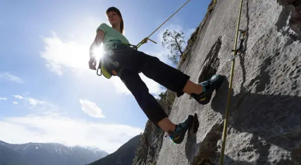 Eine Kletterin seilt sich ab. Das Abseilen bedeutet hier, sicher den Berg hinunterzukommen.