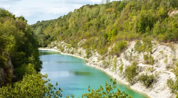 Ein malerischer Weg lädt zum **wandern am Wasser** ein. Türkisblaue Fluten schlängeln sich durch eine grüne Hügellandschaft mit steilen, weißen Ufern.