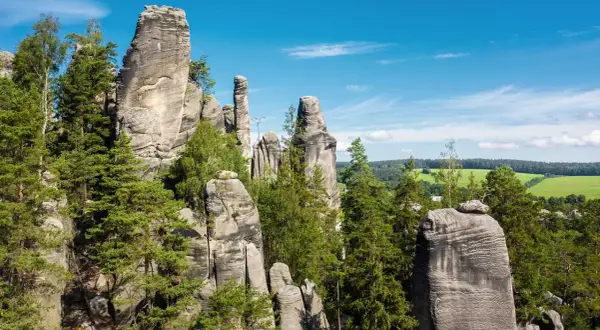 Felsformationen im Adersbacher Felsenlabyrinth, ideal zum Klettern in Tschechien. Grüne Bäume und blauer Himmel.