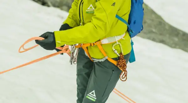 Bergsteigerin bindet mit geübten Händen einen halbmastwurf knoten. Die Seile sind bereit für die nächste Tour.