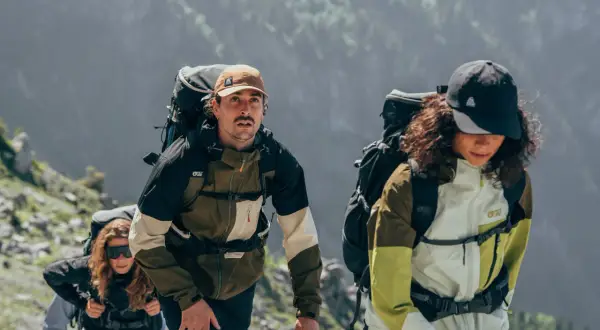 Drei Wanderer mit Rucksäcken steigen einen Bergpfad hinauf. Wie viele Kilometer schafft man wohl in 2 Stunden?