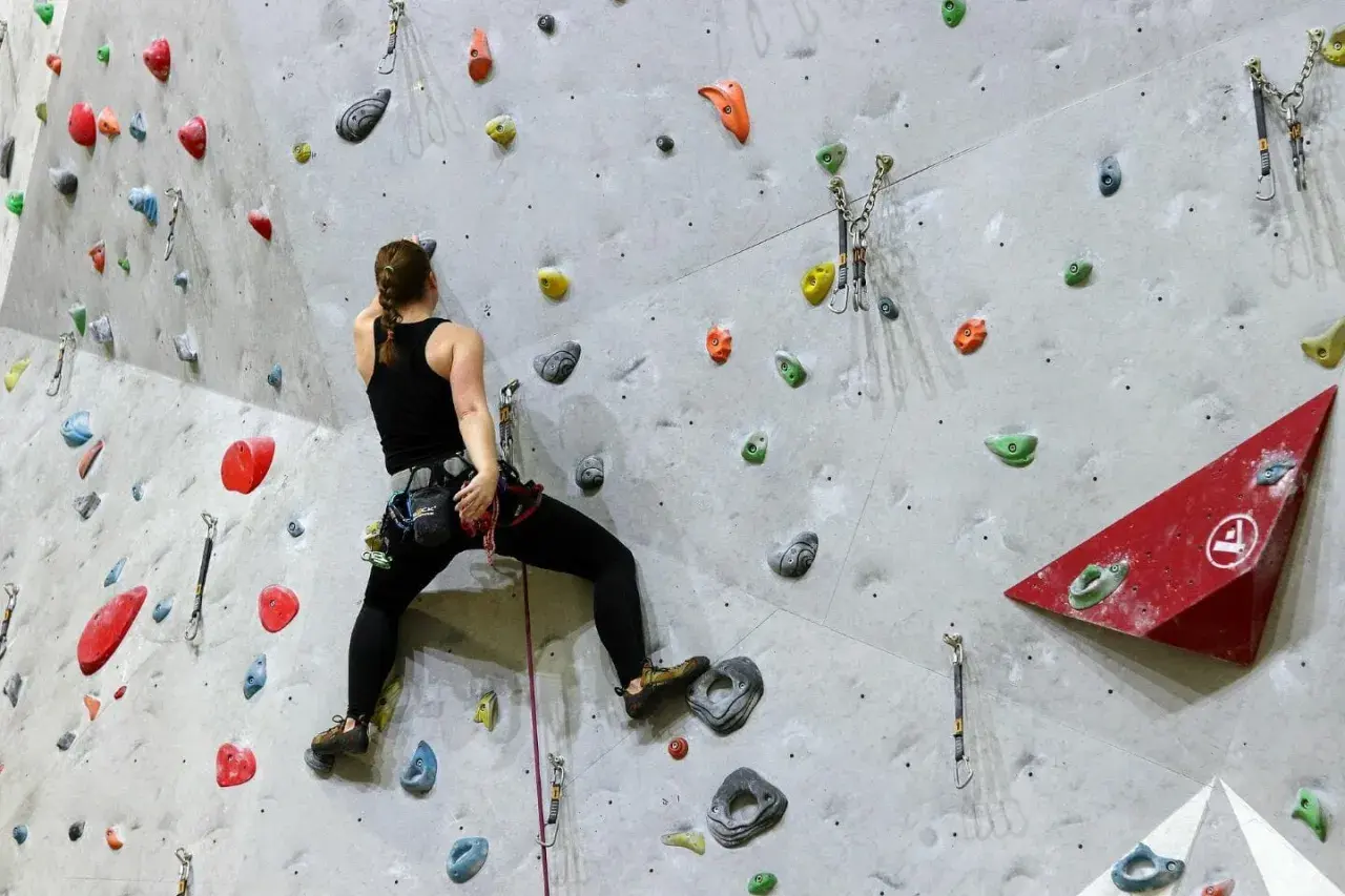 Frau beim Bouldern, sucht nach den nächsten Griffen. Gute bouldern tipps helfen, die Route zu meistern.