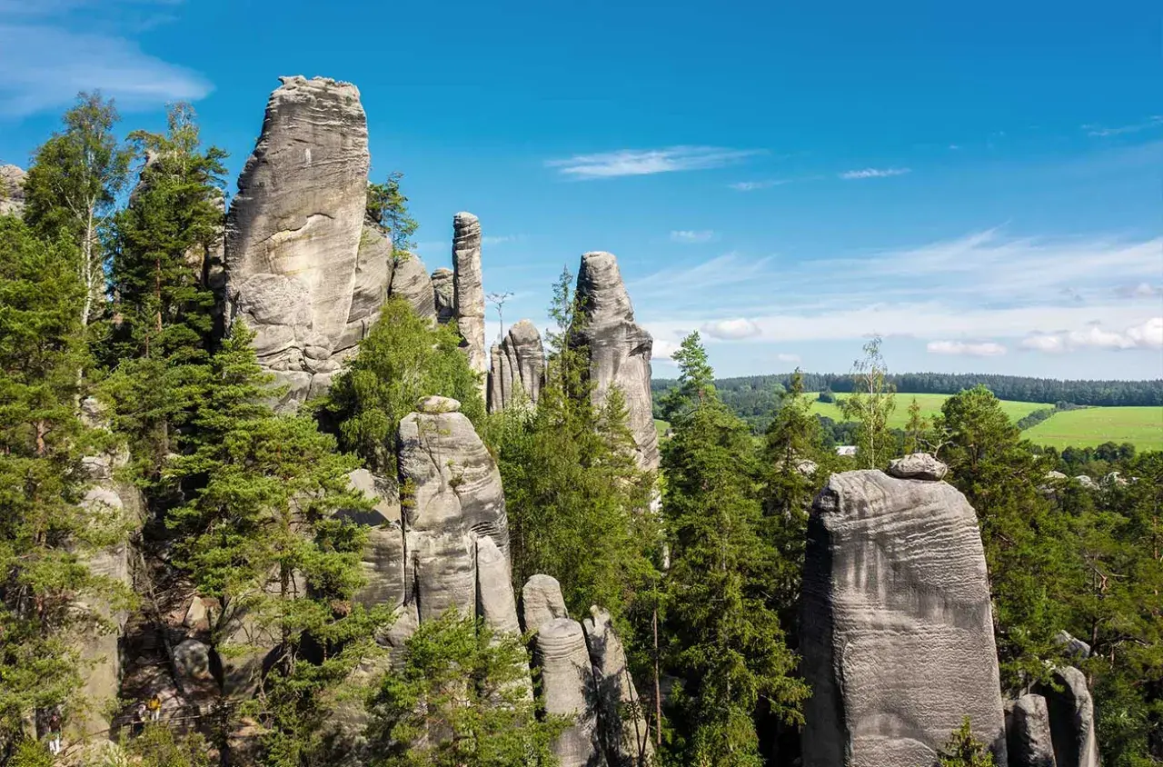 Felsformationen im Adersbacher Felsenlabyrinth, ideal zum Klettern in Tschechien. Grüne Bäume und blauer Himmel.