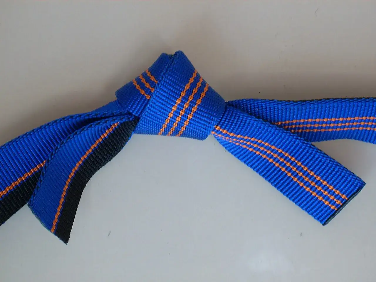 Ein blauer Bandschlinge Knoten mit orangefarbenen Streifen, der sicher und fest gebunden ist.