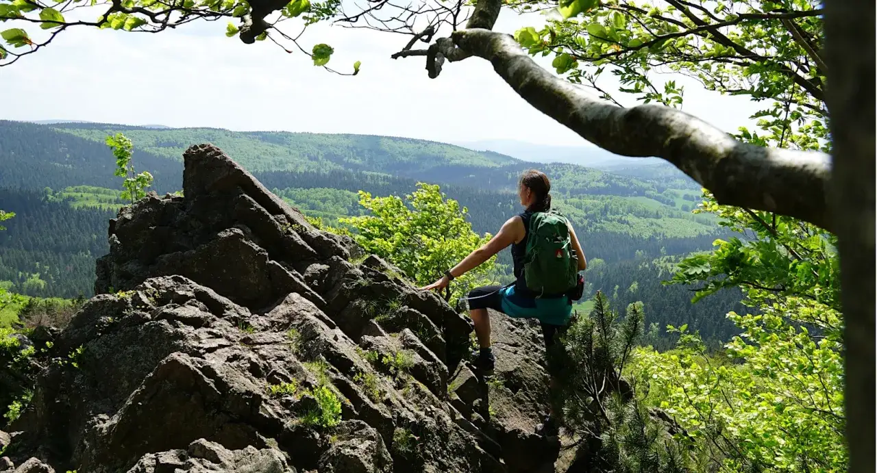 Frau mit Rucksack genießt Aussicht auf Felsen während einer 3 Tage Wanderung Deutschland.