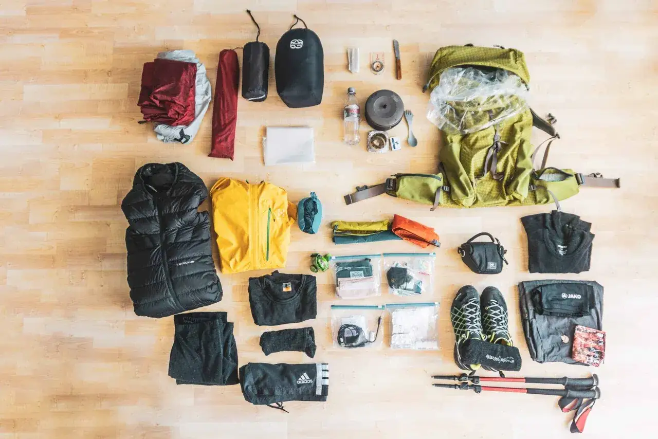 Ausrüstung für hiking vs trekking: Rucksack, Zelt, Schlafsack, Kleidung, Schuhe, Wanderstöcke, Kochutensilien, Erste-Hilfe-Set.