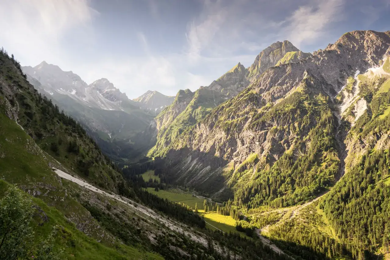 Sonnendurchflutetes Tal mit steilen Bergh&auml;ngen, ideal f&uuml;r Oberstdorf Wanderungen. Gr&uuml;ne Almwiesen und Nadelw&auml;lder.