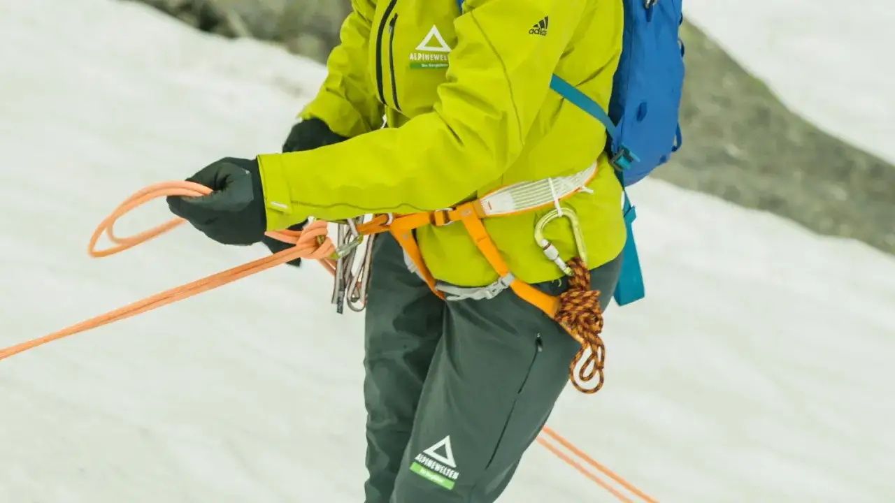 Bergsteigerin bindet den halbmastwurf knoten. Die Seile sind bereit f&uuml;r den Abstieg im Schnee.