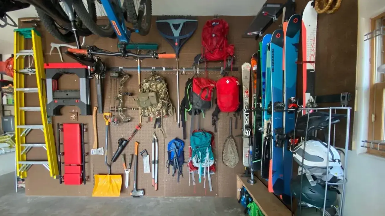 Perfekte Organisation für Outdoor-Abenteuer: Fahrräder, Skier, Rucksäcke und Werkzeuge hängen ordentlich an der Wand. Tolle Camping-Hacks für jedes Equipment!