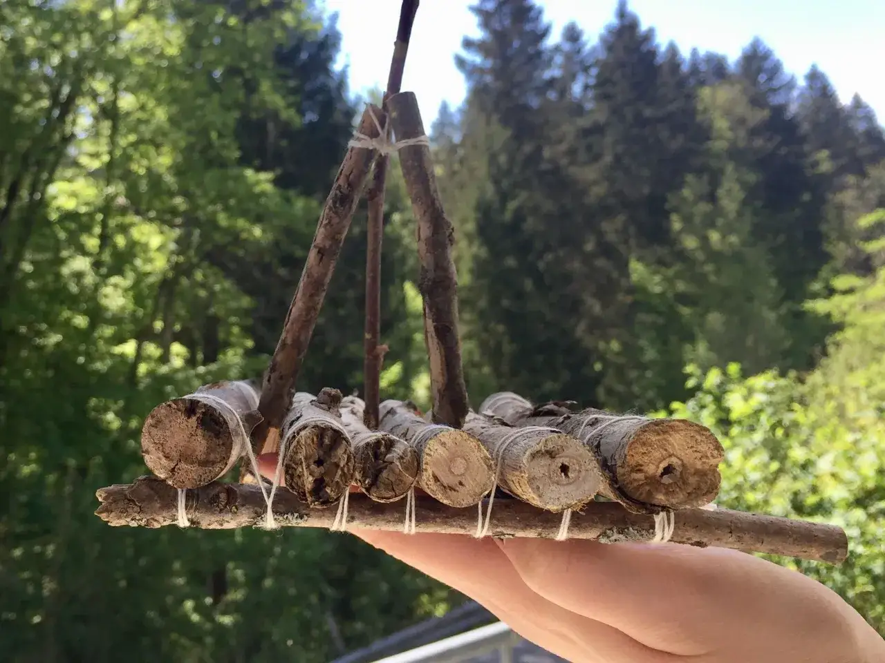 Ein selbstgebautes Floß aus Ästen und Schnur, bereit zum Einsatz auf einem Bach.