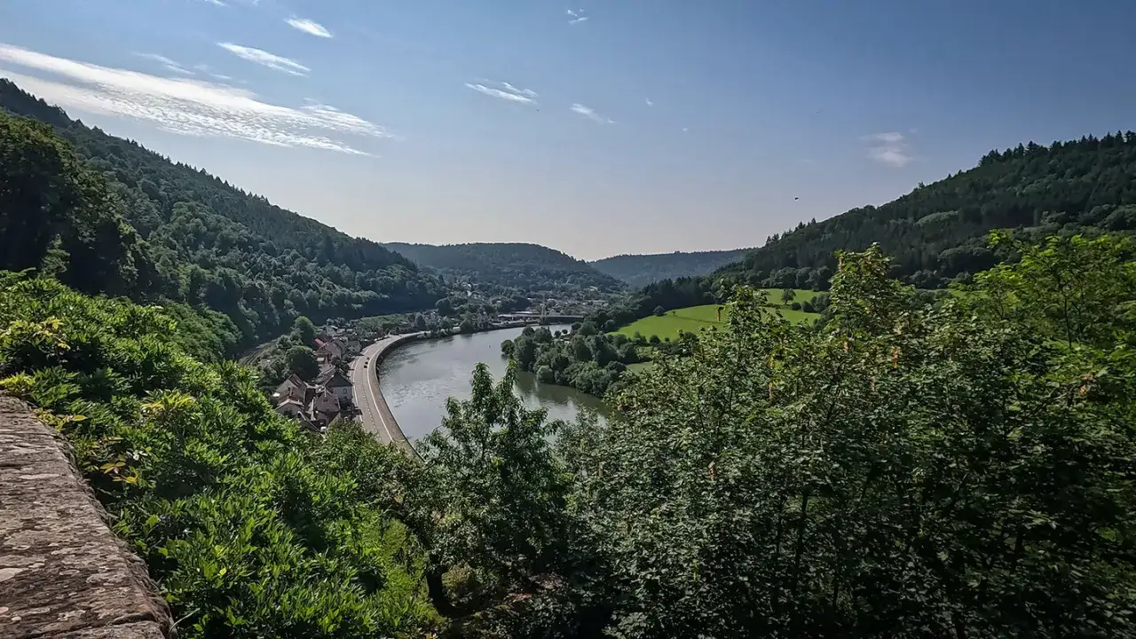 Idyllisches Tal mit Fluss, Stra&szlig;e und H&auml;usern, umgeben von bewaldeten H&uuml;geln. Perfekt f&uuml;r Odenwald Wandern.