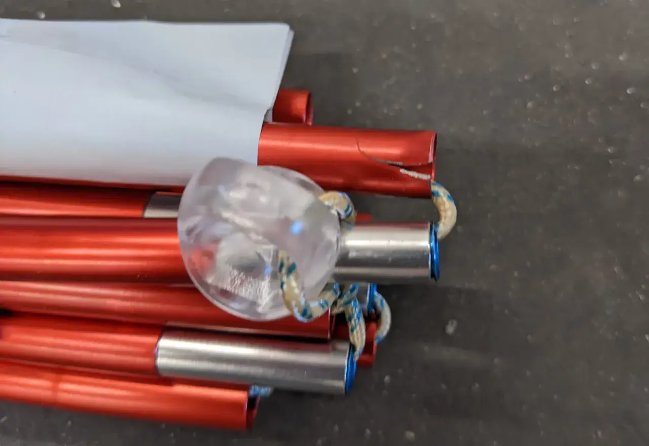 Rote Zeltstangen mit Riss, bereit f&uuml;r die zeltstange reparieren. Ein transparentes Ende mit Schnur ist sichtbar.