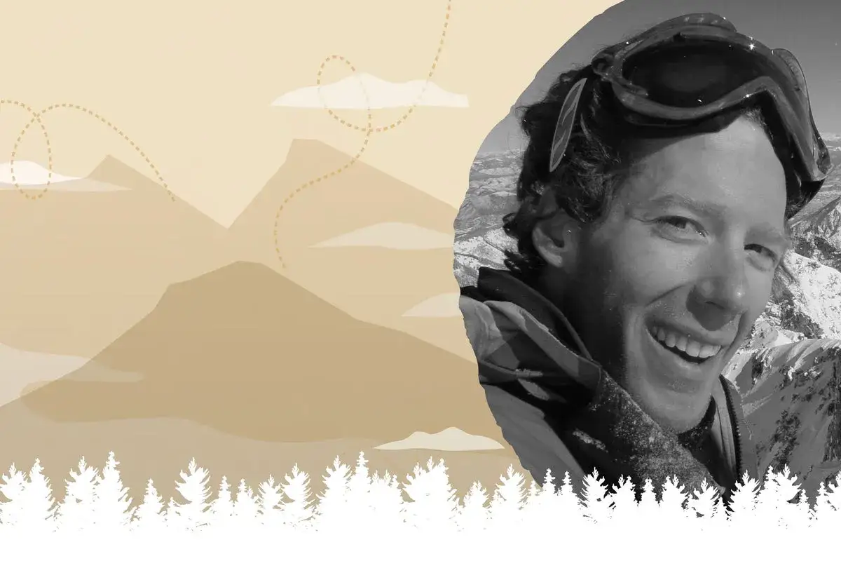 Aron Ralston heute, lachend mit Skibrille auf dem Kopf, vor einer Berglandschaft mit B&auml;umen.