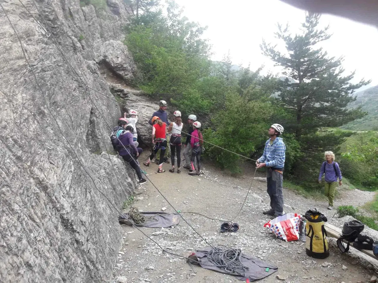 Gruppe beim Klettern in Briançon. Ein Mann sichert die Kletternden an der Felswand, während andere auf ihren Einsatz warten.