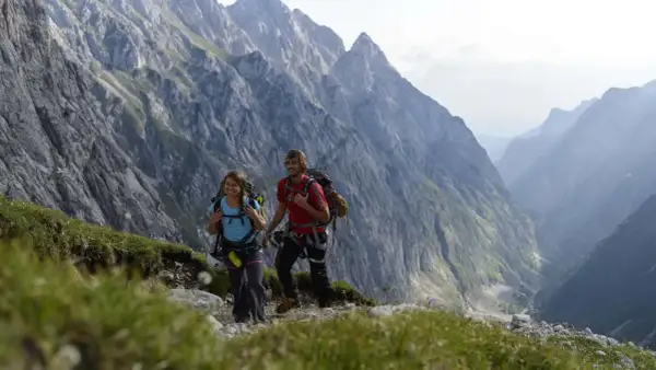 Zwei Wanderer mit Rucksäcken genießen die Aussicht auf die Berge bei Garmisch.