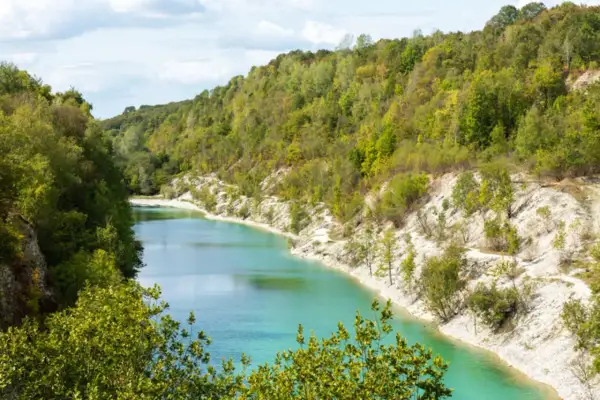 Ein malerischer Weg lädt zum **wandern am Wasser** ein. Türkisblaue Fluten schlängeln sich durch eine grüne Hügellandschaft mit steilen, weißen Ufern.