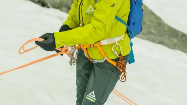 Bergsteigerin bindet mit geübten Händen einen halbmastwurf knoten. Die Seile sind bereit für die nächste Tour.